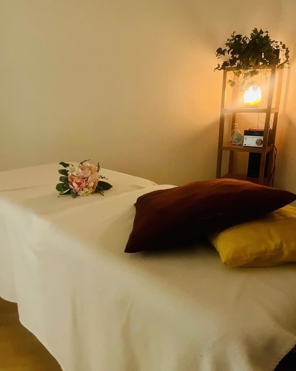 Table de massage préparée, draps blancs et lumière chaude
