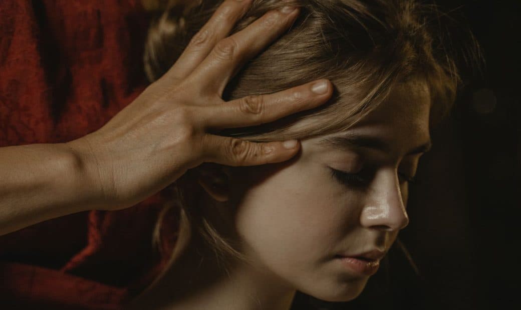 Mains massant les tempes d’une personne allongée