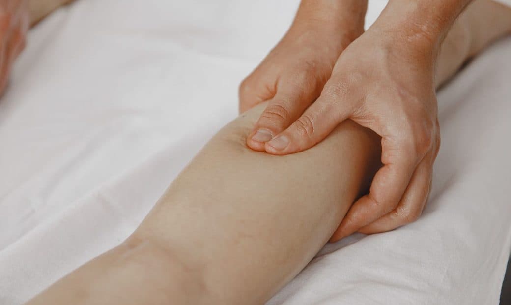 Massage appuyé du mollet, mains du thérapeute en action